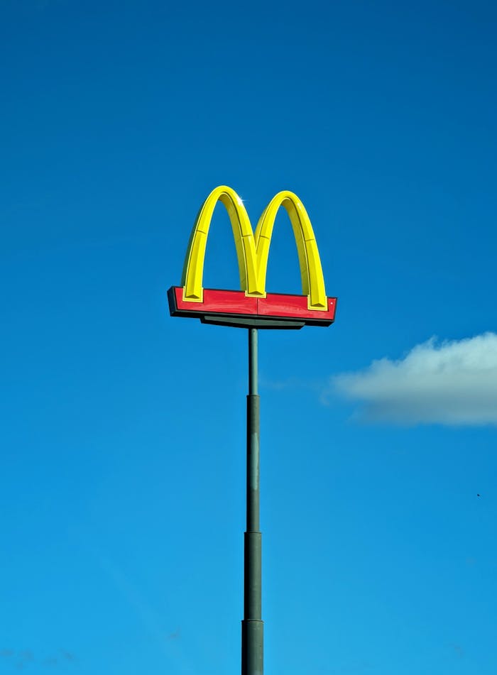 Vertical shot of McDonald's iconic golden arches sign with clear blue sky background.